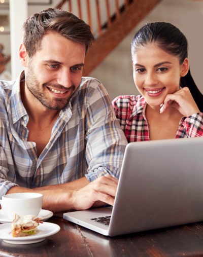 young adoptive couple looking laptop at cafe