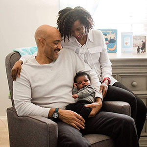 happy adoptive couple gaze down at their newly adopted baby